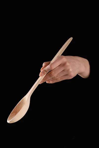 Cropped image of woman holding wooden spatula isolated on black — Stock Photo