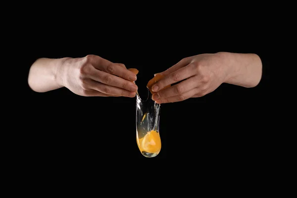 Cropped image of woman dropping chicken egg isolated on black — Stock Photo