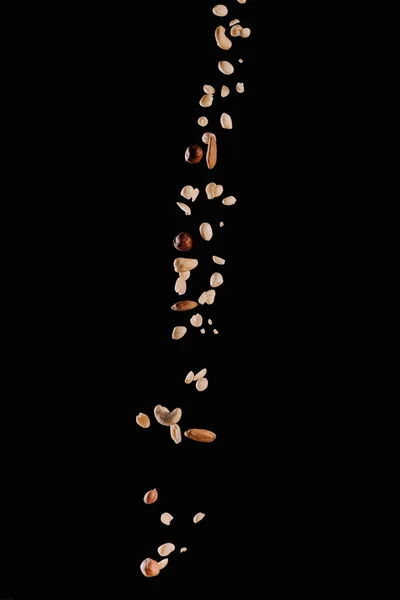 Falling yummy different nuts isolated on black — Stock Photo