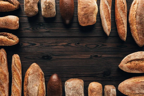 Top view of arranged loafs of bread on wooden surface — Stock Photo