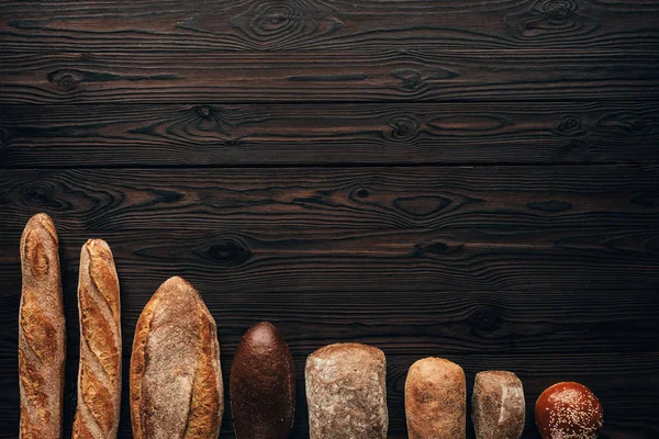 Top view of arranged loafs of bread on wooden surface — Stock Photo