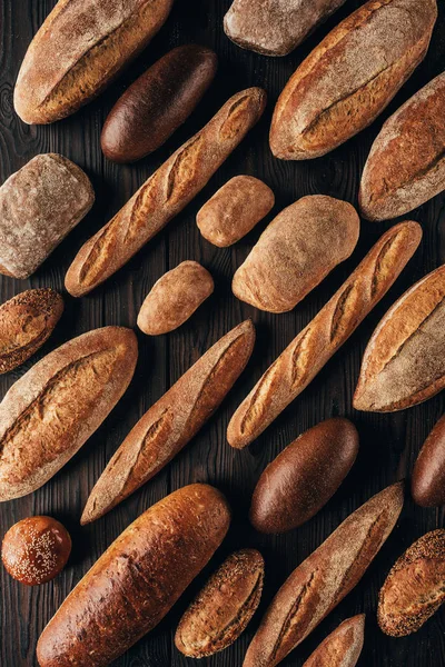 Vista superior de loafs arranjados de pão na superfície de madeira — Fotografia de Stock