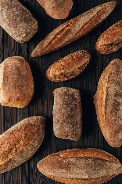 Top view of arranged loafs of bread on wooden surface — Stock Photo