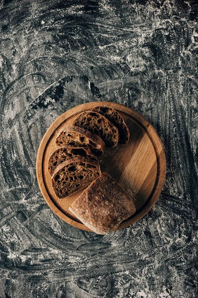 Top view of arranged pieces of bread on cutting board on dark surface with flour — Stock Photo