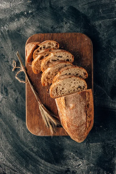 Ansicht von angeordneten Brotstücken auf Schneidebrett auf dunkler Oberfläche mit Mehl — Stockfoto