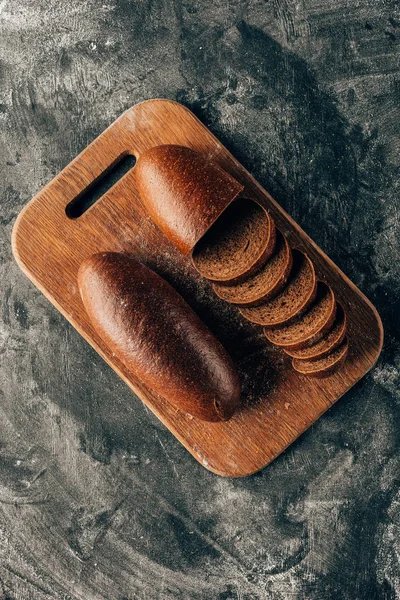 Top view of arranged pieces of bread on cutting board on dark surface with flour — Stock Photo