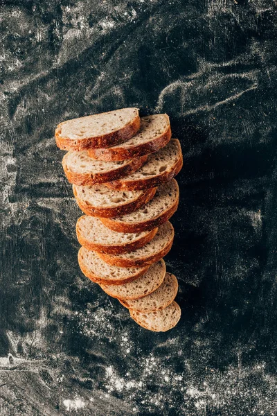 Vista superior de pedaços arranjados de pão na superfície escura com farinha — Fotografia de Stock