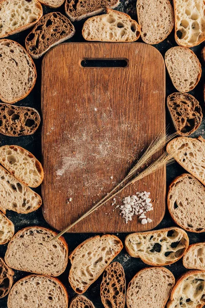 Вид зверху розташовані шматки хліба та дерев'яної обробної дошки з пшеницею та сіллю — стокове фото
