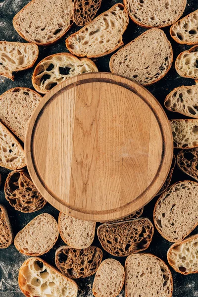 Vista dall'alto di pezzi di pane disposti e tagliere di legno vuoto — Foto stock