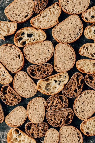 Vista dall'alto di pezzi di pane disposti su un tavolo scuro con farina — Foto stock