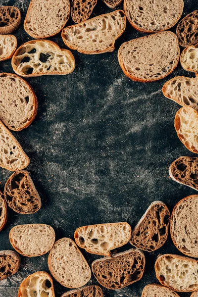 Vue du dessus des morceaux de pain disposés sur une table sombre avec de la farine — Photo de stock