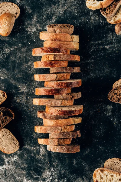 Vista superior de piezas dispuestas de pan en la mesa oscura con harina - foto de stock