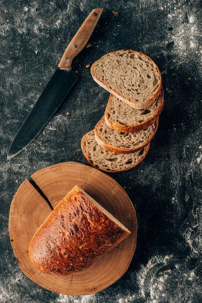 Ansicht von angeordneten Brotstücken und Messern auf dunkler Tischplatte mit Mehl — Stockfoto