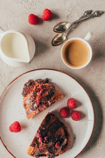 Vista superior de arranjo de xícara de café e doce pastelaria com framboesas na placa na superfície clara — Fotografia de Stock