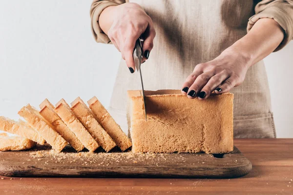 Teilansicht einer Frau, die Laib Brot auf einem Holzschneidebrett schneidet — Stockfoto