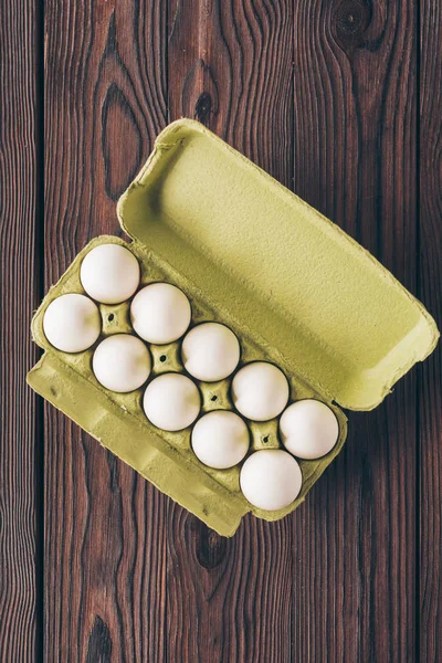 Top view of chicken eggs in eggs tray on wooden table — Stock Photo