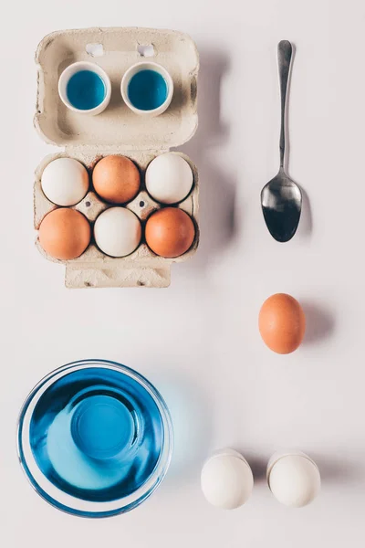 Top view of glass with blue paint for painting easter eggs on white surface — Stock Photo