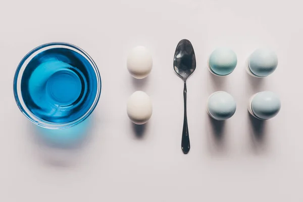 Top view of glass with blue paint and chicken eggs on stands, easter concept — Stock Photo