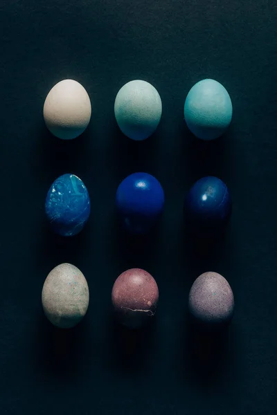 Collection de neuf œufs de Pâques peints en couleur sur une surface sombre — Photo de stock