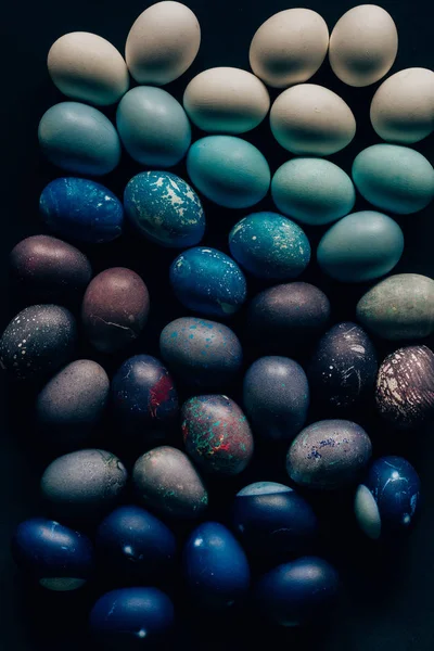 Vue de dessus des oeufs de Pâques peints en couleur sur une surface sombre — Photo de stock