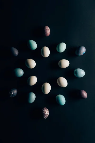 Puesta plana de huevos de Pascua pintados de colores en la superficie oscura - foto de stock