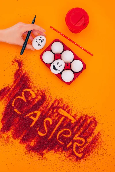 Abgeschnittenes Bild einer Frau, die ein Osterei mit Smiley auf Orange hält — Stockfoto