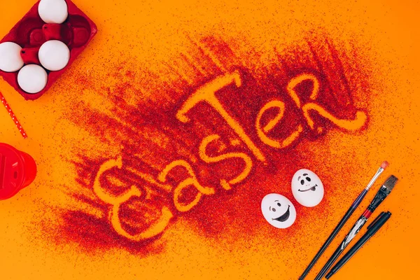 Top view of easter sign made of red sand with chicken eggs on orange — Stock Photo
