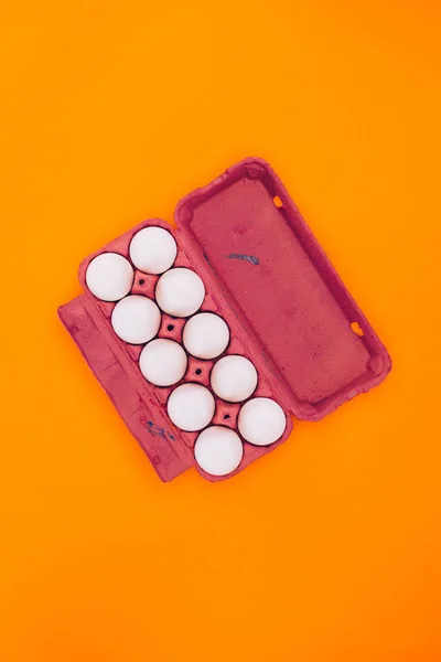 Vista superior de ovos de galinha em bandeja de ovo violeta isolada em laranja — Fotografia de Stock