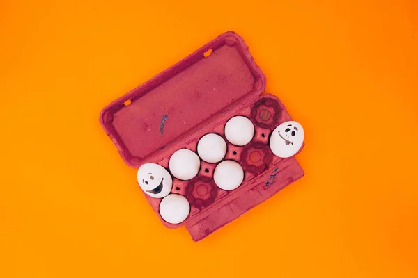 Top view of chicken eggs with smileys for easter painting isolated on orange — Stock Photo