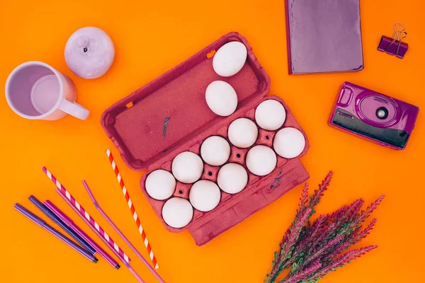 Vue du dessus des œufs de poulet dans un bac à œufs violet pour la peinture de Pâques isolé sur orange — Photo de stock