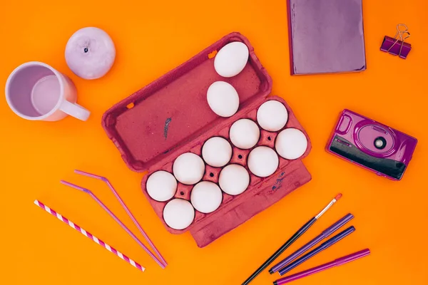 Vue surélevée des œufs de poulet dans le bac à œufs et les stylos feutres pour la peinture de Pâques isolés sur orange — Photo de stock