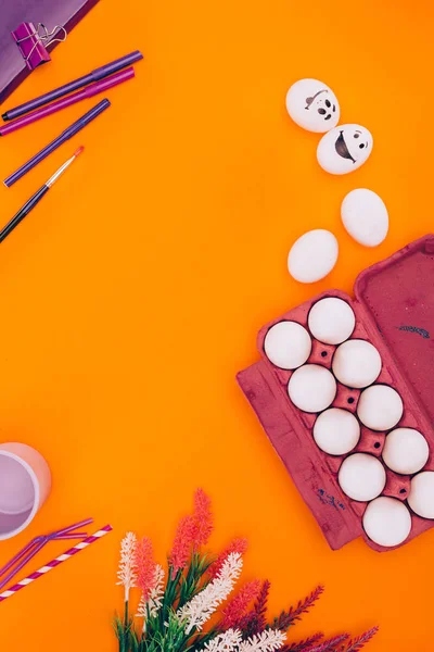 Top view of chicken eggs in egg tray and felt tip pens for easter painting isolated on orange — Stock Photo