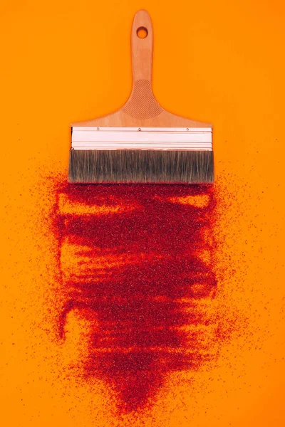 Top view of red sand for decoration and brush isolated on orange — Stock Photo