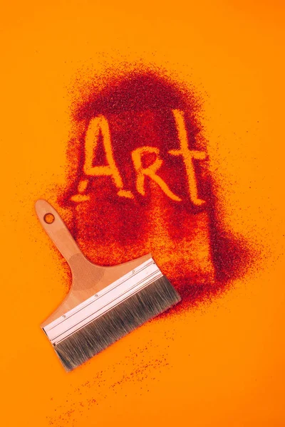 Top view of art sign made of red sand and brush isolated on orange — Stock Photo