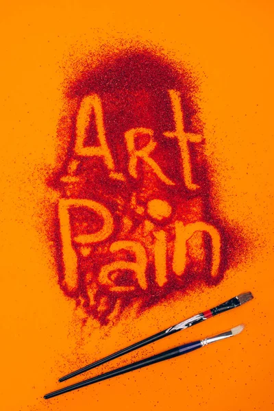 Top view of art pain sign made of red sand and brushes isolated on orange — Stock Photo