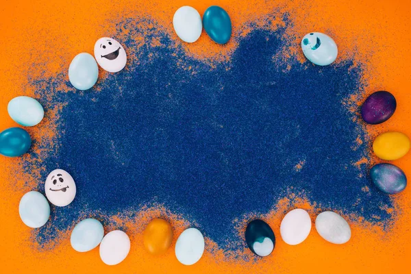 Vista superior de areia azul e ovos de Páscoa na superfície laranja — Fotografia de Stock