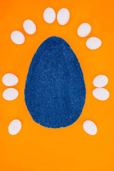 Top view of blue easter egg made of sand and chicken eggs isolated on orange — Stock Photo