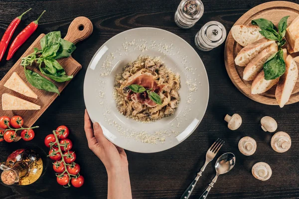 Imagen recortada de la mujer sosteniendo plato con pasta y carne - foto de stock