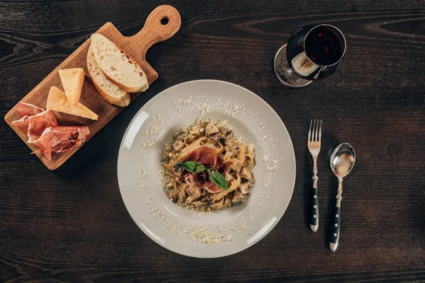 Draufsicht auf Pasta mit Fleisch und einem Glas Rotwein auf dem Tisch — Stockfoto
