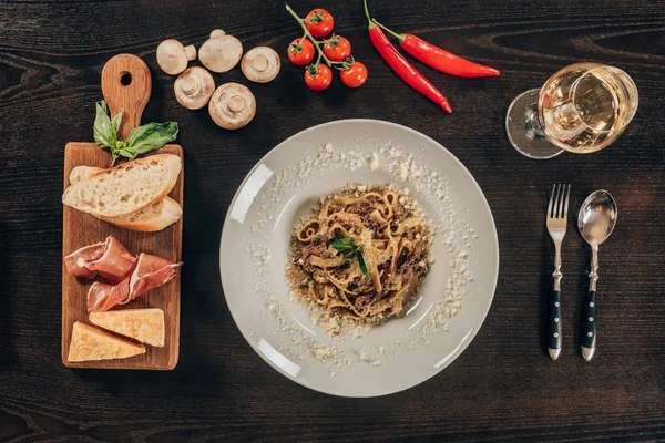 Vue du dessus des pâtes sur assiette et de la viande sur planche de bois — Photo de stock