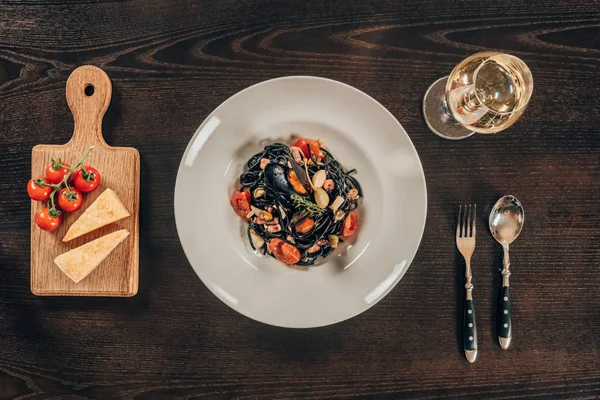 Вид сверху на спагетти с чернилами каракатицы, кальмаров и мидий с осьминогом на столе — стоковое фото