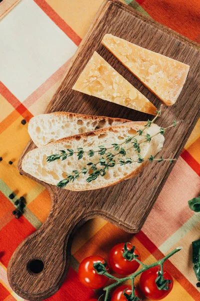 Vista elevada de baguete e queijo parmesão em tábua de madeira — Fotografia de Stock