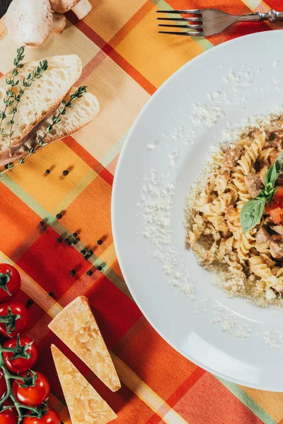 Vue du dessus des pâtes avec du porc rôti sur une serviette de table colorée — Photo de stock