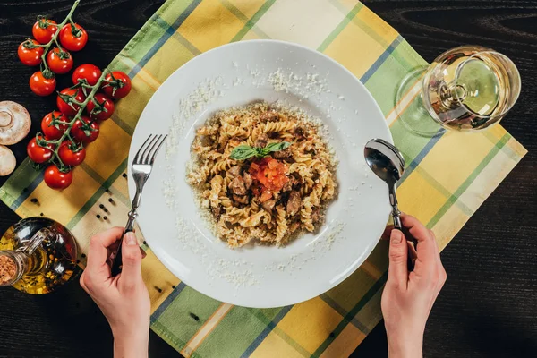 Abgeschnittenes Bild einer Frau, die Gabel und Löffel in der Hand hält und Pasta essen geht — Stockfoto