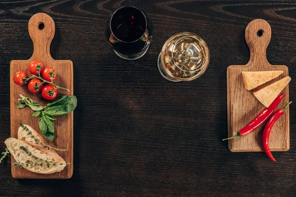 Vista superior de copas de vino y queso parmesano con verduras en la mesa - foto de stock