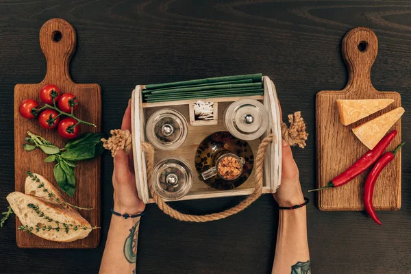 Cropped image of woman holding wooden box with olive oil and pepper grinder — Stock Photo