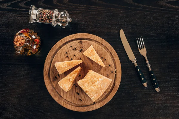 Vista superior de pedaços de queijo parmesão em tábua de madeira na mesa — Fotografia de Stock