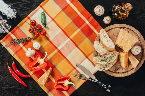 Vue du dessus de la serviette de table avec légumes et planche à découper avec fromage parmesan sur la table — Photo de stock