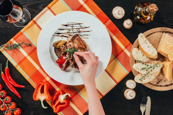 Cropped image of woman putting rosemary twig on grilled chicken — Stock Photo