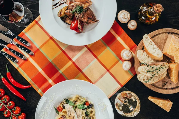 Vue du dessus du poulet et des pâtes avec filet de sandre sur la serviette de table — Photo de stock